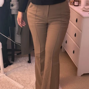 Beige byxor från Gina Tricot - Säljer ett par snygga beige byxor från Gina Tricot. De är mid waist och har en bootcut-stil som ger en riktigt schysst siluett. Perfekta för både vardag och fest! Byxorna är i ett mjukt och bekvämt material som känns skönt mot huden.