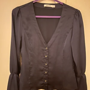 Mörk lilla/blå blus  - En jätte fin mörk lilla/blå blus köpt från NA-KD. Sitter skönt, kan vara lite kort på armarna men det är så den ska vara. En massa Söta små knappar framme💜💙