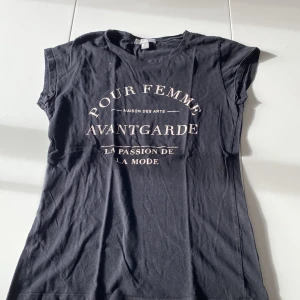 T-shirt med vitt tryck  - T-shirt köpt på New yorker. Svart lång topp med runt tryck över bröstet. Tajt modell. Inga defekter. 