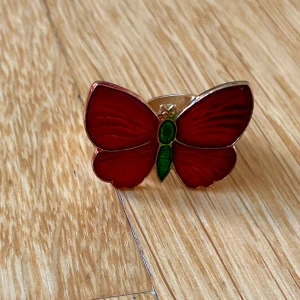 Fjärilsring - Fjärilsring i röd och grön, har guldplätering på själva ringen och baksidan. Storleken är justerbar