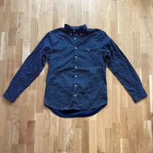 Mörkblå skjorta med stjärnmönster från GANT - Säljer en snygg mörkblå skjorta från GANT med ett coolt mini stjärnmönster. Skjortan är i slim fit och har långa ärmar. Perfekt för både vardag och fest! Den är i bra skick och redo för en ny ägare. 🌟