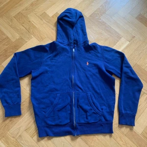 Polo Ralph lauren zip hoodie - Säljer en snygg Polo ralph lauren zip hoodie till ett bra pris, den är i bra skick men lite nopprig på insidan men såklart ingenting som syns när man har på sig den. Den saknar snöret som ska sitta runt luvan. Priset är såklart diskuterbart!