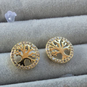 Guldörhängen med trädmotiv -  Eleganta guldörhängen med ett vackert trädmotiv i mitten. Runt trädet finns en glittrande kant av små stenar som ger en extra touch av glamour.NYA
