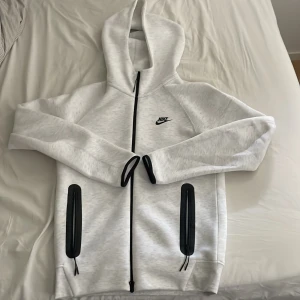 Nike tech fleece - Den nya generationens tech fleece, i en extremt fin ljusgrå färg. Skicket är nyskick då den är använd 1-2 gånger. Storlek XS, men passar även S väldigt bra då de nya är större i storlekarna. Vid fler frågor eller funderingar är det bara att skriva :)
