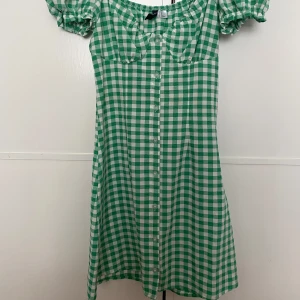 Rutig klänning från H&M  - Grönvit rutig sommarklänning från H&M. Endast använd en gång och säljs därför.. Pris går att diskutera.