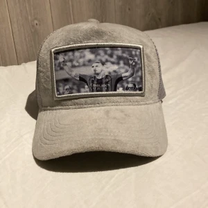 Velvetkeps lozama headwear  - En grå velvetkeps från lozama nästintill oanvänd. Ett motiv med Zlatan när han röker en ciggar i milantröja  Ny pris ca 500kr pris kan diskuteras 