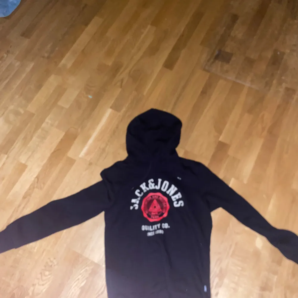 Säljer en oanvänd hoodie från Jack & Jones med tryck i rött och vitt på framsidan. Perfekt för en casual look och bekväm att ha på sig. Passar perfekt till höst och vinter. Hoodies.