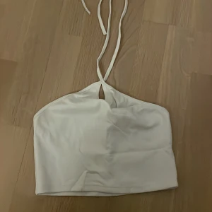 Vit crop top från Zara - Croppad vit topp, Stretchig. Halterneck och knyts i nacken. Storlek M men liten i storleken! Motsvarar en S