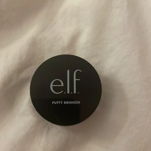 e.l.f. Putty Bronzer - Säljer en e.l.f. Putty Bronzer i en praktisk liten burk. Den har en krämig konsistens och en naturlig brun nyans som ger en solkysst look. Perfekt för att skapa definition och värme i ansiktet. Jag har bara rört i den för att kolla färg