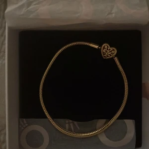 Guldarmband från Pandora - Elegant guldarmband från Pandora med ett hjärtformat lås. Perfekt för att ge en touch av lyx till din stil. Levereras i originalförpackning. Har kvitto och allt, aldrig använt. 