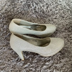 Glittriga pumps i silver - Säljer ett par eleganta glittriga pumps i silver. Perfekta för speciella tillfällen med en bekväm klack och rund tå. Passar utmärkt för att ge en touch av glamour till din outfit.