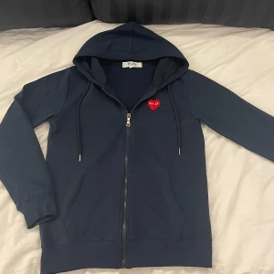 Comme des Garçons full-zip hoodie  - Säljer denna full-zip hoodien från Cdg. | Skicka är så gott som nytt. | Den är i en mörkblå/marinblå färg men en röd logga. | Det är bara att höra av sig om man har några frågor eller funderingar kring hoodien⭐️⭐️⭐️