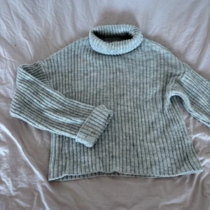 Grå ribbad polotröja - Mysig grå ribbad polotröja med långa ärmar. Perfekt för kyliga dagar med sin stickade design och bekväma passform.