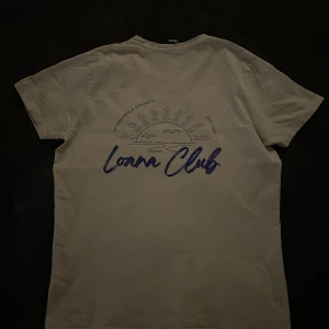 Vit T-shirt med tryck - Snygg beige t-shirt med ett coolt tryck av en solnedgång och text i blått på baksidan. Perfekt på en fet sommar outfit!🤩