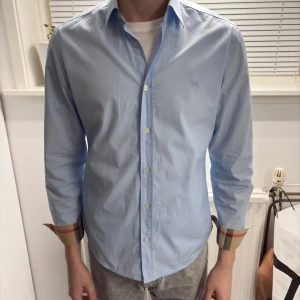 Burberry Skjorta - En riktigt schysst Burberry skjorta i väldigt fint skick. En snygg ljusblå färg, storlek M.