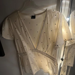 Vit prickig omlottopp - Säljer en söt vit omlottopp från Gina tricot med små svarta prickar. Toppen har korta ärmar och knytning på baksidan eller framsidan om man vill. Använd endast 1 gång. Skicka gärna prisförslag😊