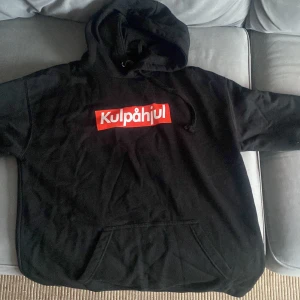 Svart hoodie med tryck från Kulpåhjul - Säljer en svart hoodie med tryck från Kulpåhjul. Framsidan har en röd och vit logga, medan baksidan har ett stort tryck med texten 'Boost Loading' och en bild av turbos. Perfekt för bilentusiaster!
