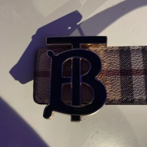 Rutig skärp från Burberry - Snyggt skärp från Burberry med ett rutigt mönster och en stor, stilren spänne med logotyp. Skärpet har en klassisk design som passar perfekt för att lyfta vilken outfit som helst. Jag har haft bältet i ett år och använts titt som tätt. Finns så man kan göra fler hål. Det ända som är slitet på bältet är där jag så kallt mitt hål det hålet jag använder. PRISET KAN DISKUTERAS!!!