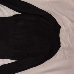 Svart tröja från Massimo Dutti - Elegant svart tröja från Massimo Dutti i mjukt material. Den har en åtsittande resårband nedtill och vid ärmsluten:) gjord med merinoull bomull