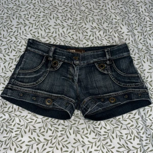 Mörkblå jeansshorts med nitar - Snygga mörkblå jeansshorts med coola nitar och detaljerade sömmar. Shortsen har fickor både fram och bak samt bälteshällor. Perfekta för en avslappnad stil.