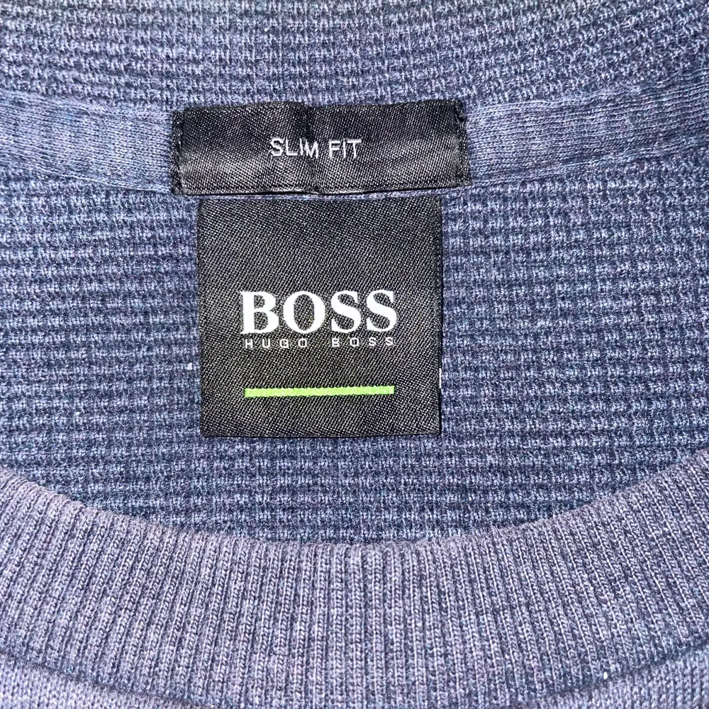 Säljer en stilren blå tröja från Hugo Boss med logotyp framtill. Tröjan har en slim fit passform och är perfekt för en avslappnad men ändå snygg look. Liten fraktur som knappt märks på vänster sida armbåge. . Neuletakit & Villapaidat.