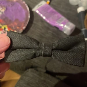 Svart fluga med justerbart band - Elegant svart fluga med ett justerbart band och spänne för enkel användning. Perfekt för formella tillfällen.