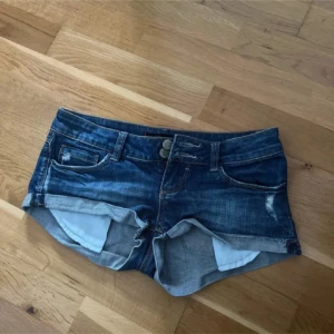 Blå lågmidjade jeansshorts - Säljer ett par snygga  blå lågmidjade  jeansshorts med slitna detaljer sitter så fint, midjemåttet är 37cm 