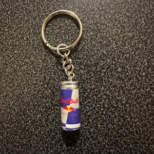 Nyckelring med Red Bull-burk - Cool nyckelring med en liten Red Bull-burk som hänge. Perfekt för att hålla koll på dina nycklar med stil. Burken är detaljerad och har den klassiska blå och silverfärgen med Red Bull-loggan.