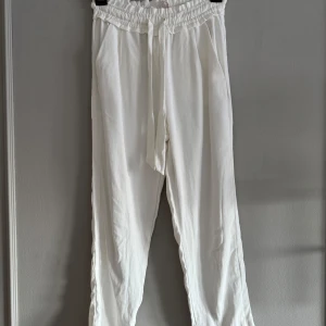 Vita byxor med knytband - Snygga vita byxor med elastisk midja och knytband för en bekväm passform. Perfekta för en avslappnad stil.