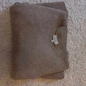 Beige stickad tröja från Other Stories  - Mysig beige stickad tröja från other Stories med rund hals och ribbade detaljer vid ärmslut och nederkant. Perfekt för kyliga dagar.