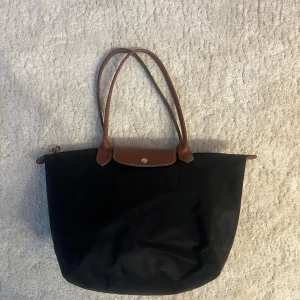 Svart tote bag från Longchamp - Modellen: Le Plaige original L tote bag i svart. Själva väskan är i mycket bra skick och var köpt för 140€