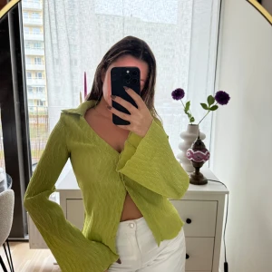 Ribbad blus  - Trendig blus  med ribbad textur och knappar framtill. Blusen har långa, vida ärmar och en stilren krage, perfekt för en färgglad look. Endast testad 