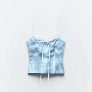 Blå och vit rutig linnetopp från Zara - Söt blå och vit rutig linnetopp från Zara med spetsdetaljer och knytband framtill. Dessa ser mer ut som en rosett när den väl är p. En liten smink fläck fram men syns ej vid användning.