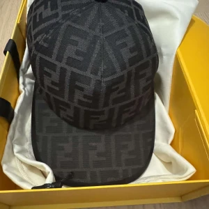 Fendi keps  - Snygg svart keps från Fendi med ett diskret mönster och justerbart band baktill. Perfekt för en stilren look.