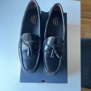 Svarta loafers från G.H. Bass & Co. - Snygga svarta loafers med tofsdetaljer från G.H. Bass & Co. Perfekta för en stilren look. Skorna har en klassisk design med rundad tå och är tillverkade i skinn.