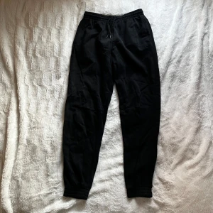 Svarta mjukisbyxor från H&M Divided - Säljer ett par svarta mjukisbyxor från H&M Divided. Byxorna har en elastisk midja med snörning för justerbar passform. Perfekta för en avslappnad stil. Mått syns på bilderna🤗