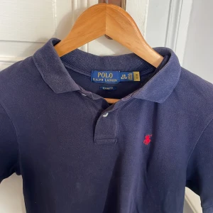 Mörkblå piké från Ralph Lauren - Säljer en klassisk mörkblå pikétröja från Ralph Lauren med den ikoniska röda loggan på bröstet. Nypriss ca 1400kr, pris kan diskuteras. L i barnstorlek, ca XS men passar S i herr.