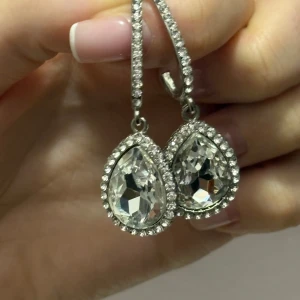 Glittriga droppformade örhängen - Eleganta droppformade örhängen med stora, klara stenar omgivna av mindre gnistrande stenar. Perfekta för att ge en lyxig touch till din outfit.