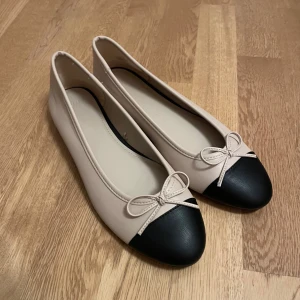 Beige och svarta ballerinaskor med rosett - Säljer dessa svarta och beiga ballerinaskor. De är aldrig använda.🌸💕