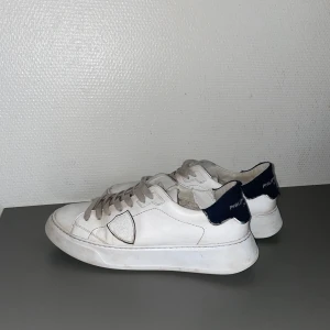Vita sneakers från Philippe Model - Snygga vita sneakers från Philippe Model med mörkblå detaljer på hälen…Skick  7/10 lagat dem på insidan på ena skon…Orginalpris: 2700kr Kvitto finns!
