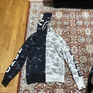 Bape Hoodie Svart och Vit - Storlek M, liten bränd skada vid axeln som syns knappt. Har inte haft på mig den mycket. Köpte den för 1800kr. Lite kortare vid armarna. Kan skicka mer bilder om du behöver.