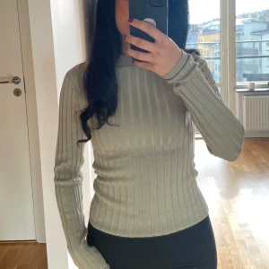 Grön ribbad tröja - Säljer en superfin grön ribbad tröja med lång ärm. Perfekt för höst och vår, den är både stilren och bekväm. Tröjan har en tight passform som framhäver figuren. OBS: liten i storleken så passar xs-s Nyskick!
