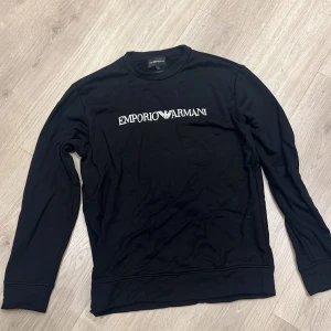 Svart långärmad tröja från Emporio Armani - Säljer en svart långärmad tröja från Emporio Armani i nyskick, ej använd, endast legat i garderoben under en lång period, Perfekt för alla tillfällen