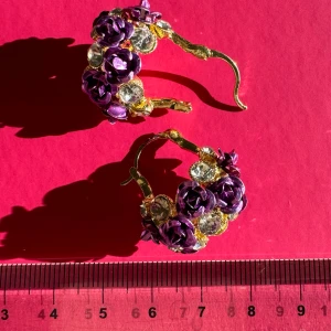 Lila och guldiga örhängen med blommor och stenar - NYA superfina örhängen i guld med lila blommor (rosor) och glittrande stenar. De är formade som små hoops och har en härlig blommig design som verkligen sticker ut. Romantiska i stilen. Hämtas på Hägerstensåsen eller ök 💜
