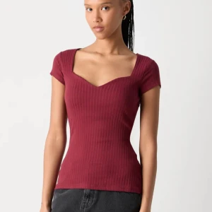 Vinröd ribbad topp - Säljer en snygg vinröd ribbad topp med korta ärmar och en v-ringad hals. Perfekt för både vardag och fest!💛🌟