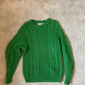 Grön stickad tröja från McONeill - Säljer en superfin grön stickad tröja från McONeill. Den har ett snyggt flätmönster och är perfekt för kyliga dagar. Tröjan är långärmad och har ribbade muddar vid ärmslut och nederkant. Perfekt för höst och vinter!