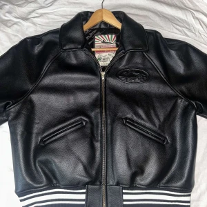 Svart skinnjacka från Corteiz - Säljer en svart skinnjacka från Corteiz i storlek XL. Jackan är i nyskick och har en cool broderad logga på ryggen. Den har dragkedja framtill och ribbade muddar i svart och vitt. Perfekt för höst och vår, och ger en snygg och tuff look. Tillverkad i Turkiet av 100% läder. (ÄKTHET KAN INTE BEVISAS) pris går att diskutera vid snabb affär 