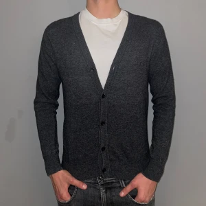 Knit Button Cardigan - Tja, säljer nu denna riktigt sköna tröjan, perfekt till hösten och vintern. Säljes då den börjar bli lite för liten, personen på bilden är 184-185 cm lång. Skick 8/10. För mer info eller bilder skicka ett meddelande!