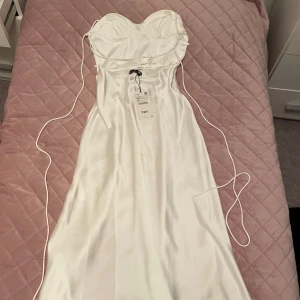 Klänning - Helt ny vit silk klänning med en slit på låret från Zara! Ryggen är öppen (första bilden)! Helt ny och aldrig använd🤍 Skriv om du vill se fler bilder💕Köpte den ett tag sen därför finns den inte längre på lager hos de! 