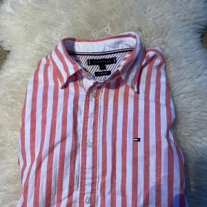 Röd- och vitrandig skjorta från Tommy Hilfiger - Säljer en  röd- och vitrandig linneskjorta från Tommy Hilfiger. Den är knappt använd och är i storlek M